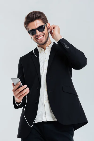 Feliz alegre hombre de negocios guapo escuchando música con auriculares y teléfono inteligente — Foto de Stock