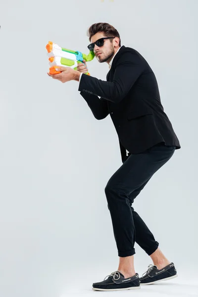 Ganzkörperporträt des fokussierten Geschäftsmannes, der mit Wasserpistole schießt — Stockfoto