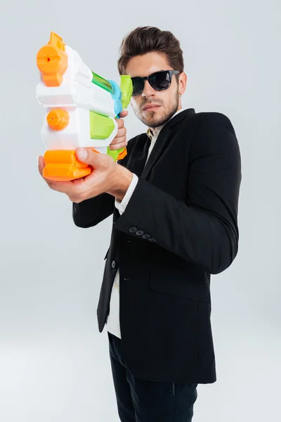 Geschäftsmann mit Sonnenbrille und Anzug schießt mit Wasserpistole — Stockfoto