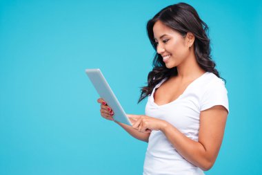 Tablet bilgisayar kullanan gülümseyen genç bir kadının yan görünümü