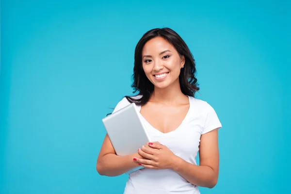 Souriant jeune femme tenant un ordinateur tablette et regardant la caméra — Photo