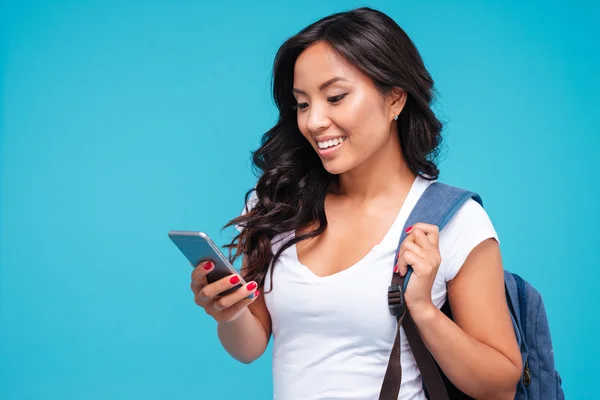 Vrolijke jonge Vietnamese meisje met rugzak met behulp van smartphone — Stockfoto