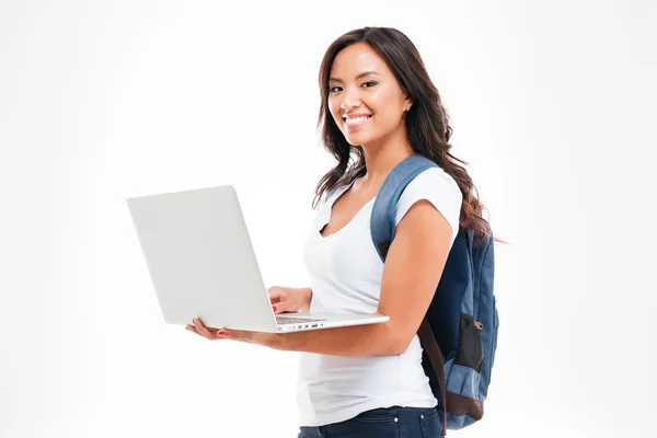 Happy asian student girl with backpack standing and holding laptop — Stock Photo, Image