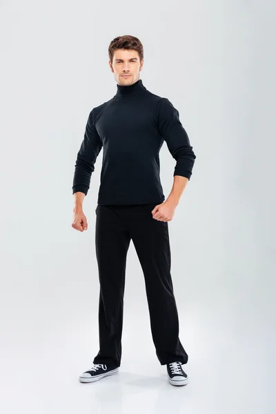 Volle Länge des starken jungen Mannes in schwarzer Kleidung stehend — Stockfoto