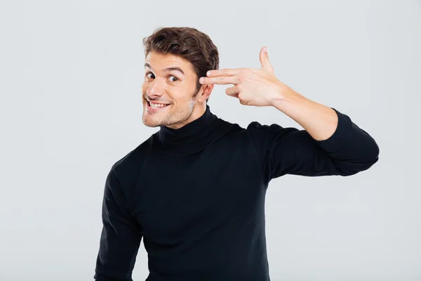 Verrückter lächelnder Mann mit Fingern an die Schläfe wie eine Waffe — Stockfoto