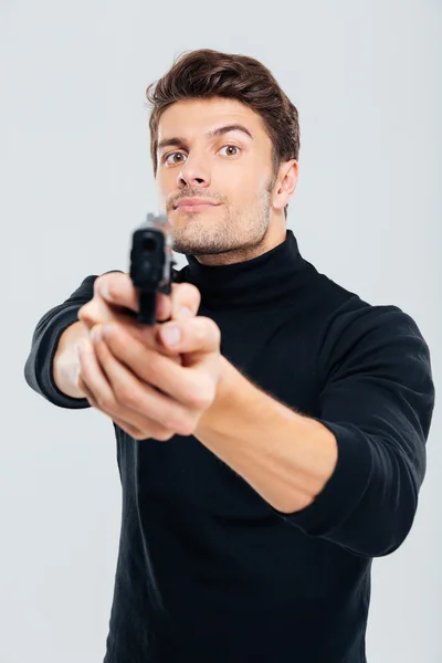 Serious young man standing and aiming gun on you — Stock Photo, Image