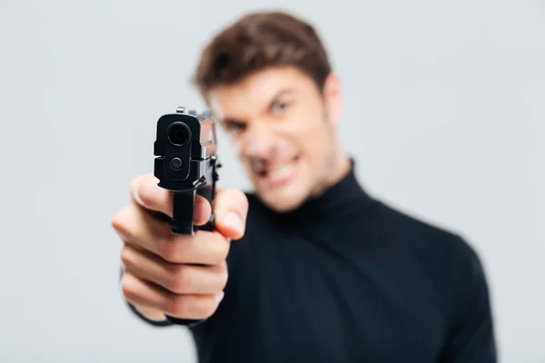 Nahaufnahme eines wütenden jungen Mannes, der mit einer Waffe auf dich zeigt — Stockfoto