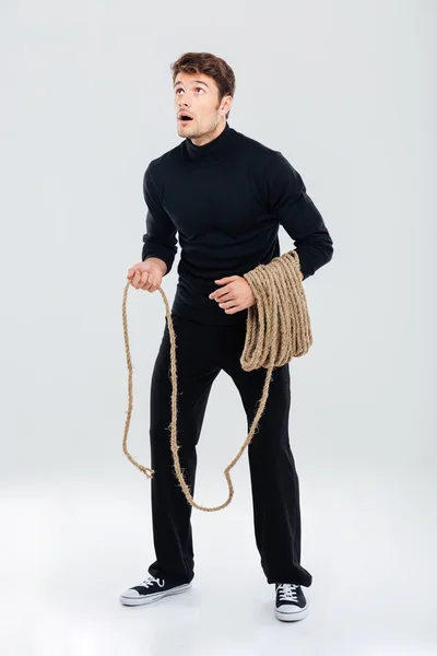 Erstaunt junger Mann mit Seil stehend und aufblickend — Stockfoto
