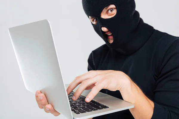 Closeup of criminal man in balaclava using laptop — Stock Photo, Image