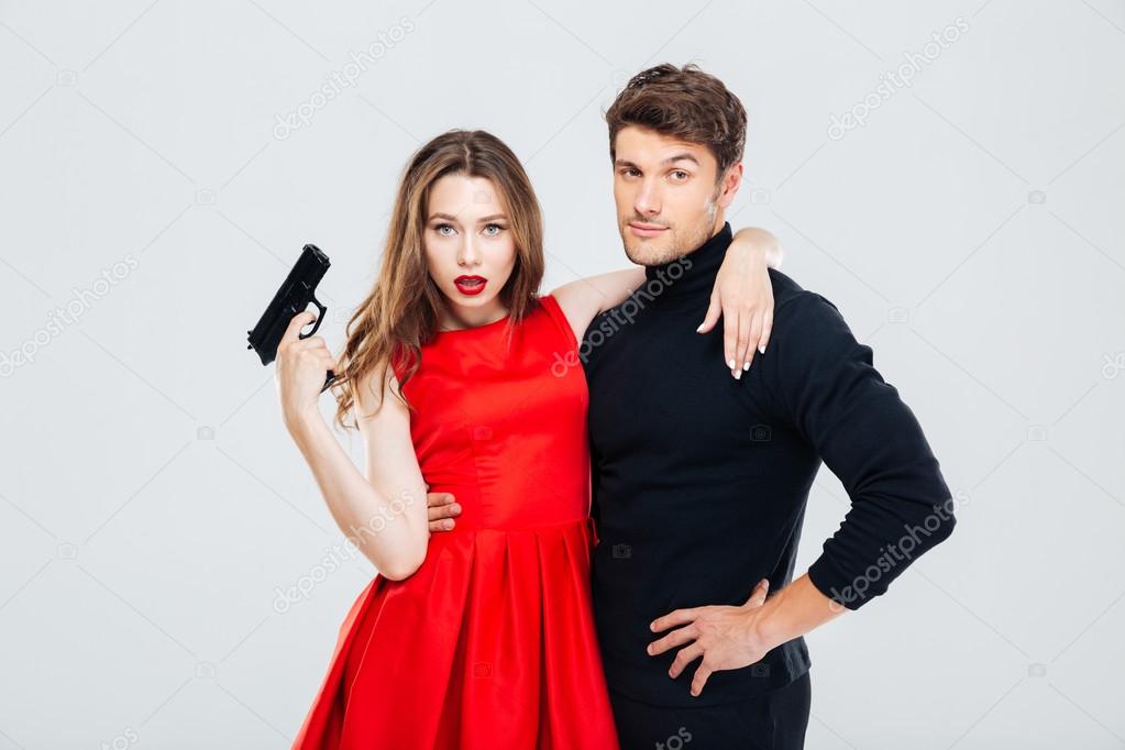 Beautiful young couple with gun standing and hugging