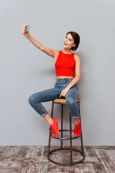 Mujer joven sonriente haciendo foto selfie en el teléfono inteligente — Foto de Stock