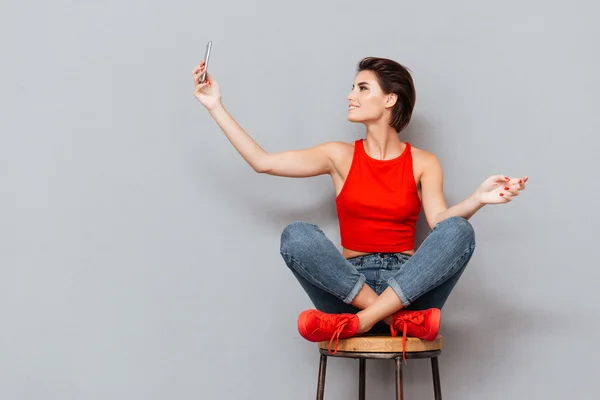 Smiling young woman making selfie photo on smartphone — Stock Photo, Image