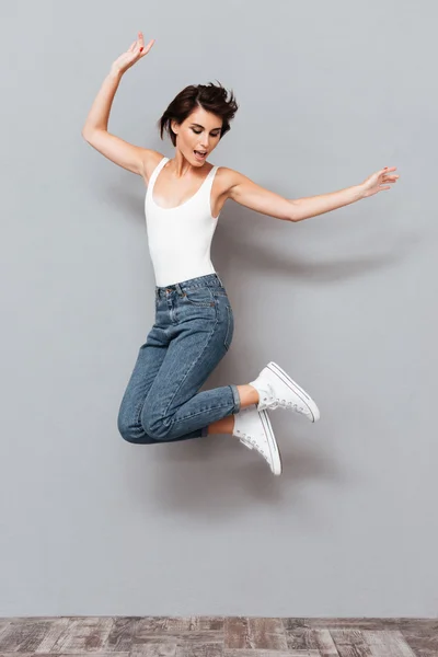 Smějící se mladá brunetka skákající — Stock fotografie
