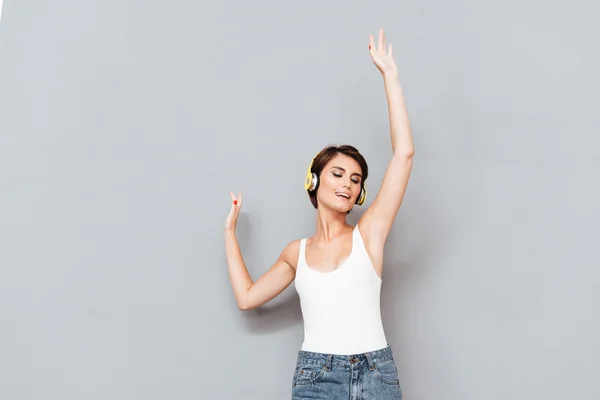 Woman listening music in headphones with raised hands up — 图库照片