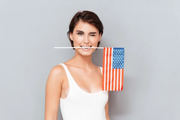 Щасливі молода жінка тримає прапор США в зуби і підморгує — стокове фото