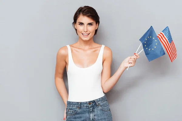 Patriotic happy woman holding european and usa flags — Stock Photo, Image