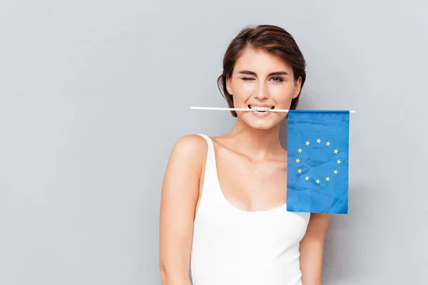 Mujer feliz sosteniendo bandera europea en los dientes y guiños —  Fotos de Stock