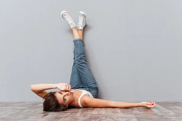 Smiling beautiful woman lying on the floor with raised legs — Stock Photo, Image