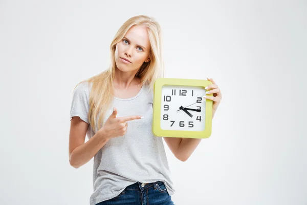 Retrato de una mujer joven señalando con el dedo el reloj de pared — Foto de Stock