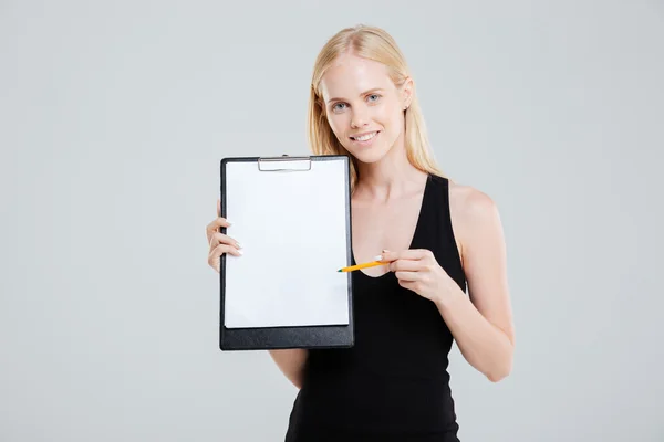 Mujer de negocios sonriente apuntando al portapapeles en blanco —  Fotos de Stock