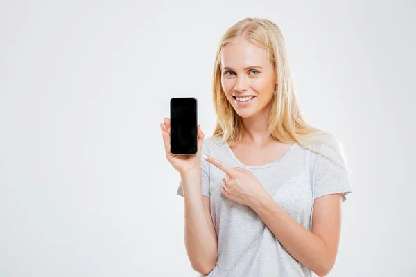 Smiling young woman pointing finger at blank smartphone screen — Stock Photo, Image
