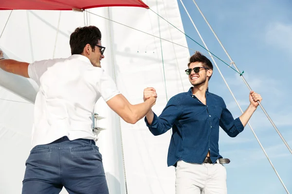 Due giovani uomini belli che salutano in piedi sullo yacht — Foto Stock
