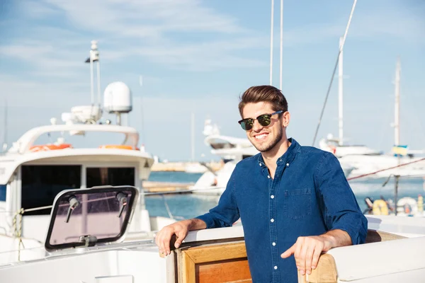 Uomo barbuto che indossa occhiali da sole e in piedi su uno yacht — Foto Stock