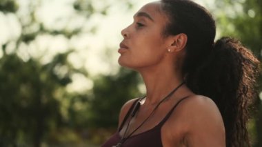 Yakışıklı, Afro-Amerikan bir kadın parkta egzersiz yapıyor.