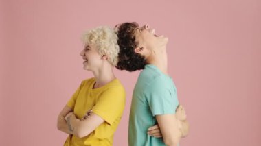 Gülümseyen genç kız ve erkek kardeş pembe arka planda tek başlarına poz veriyorlar.