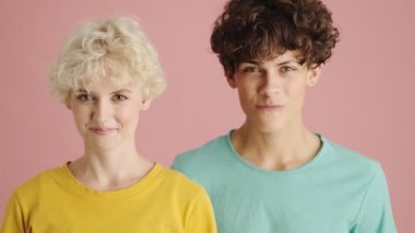 Çekici erkek ve kadın, pembe arka planda izole bir şekilde sessizce bekliyorlar.