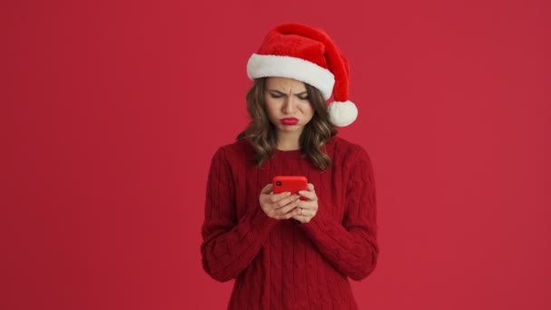 Niezadowolona Kobieta Ciepłym Czerwonym Swetrze Świątecznym Kapeluszu Używa Swojego Smartfona — Wideo stockowe