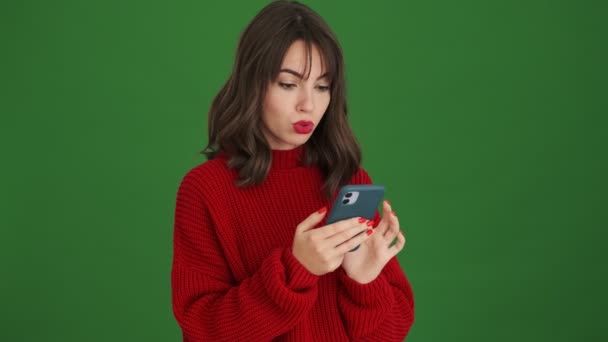 Szczęśliwa Młoda Kobieta Czerwonym Swetrze Wykonuje Gest Zwycięzcy Pomocą Smartfona — Wideo stockowe