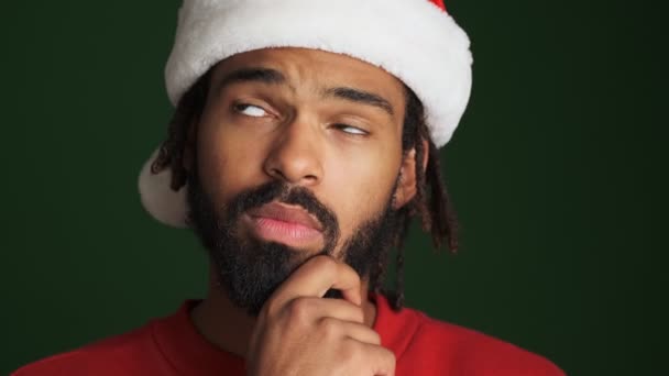 크리스마스 모자를 아프리카 남자가 배경으로 고립되었다고 생각하는 젊은이 — 비디오