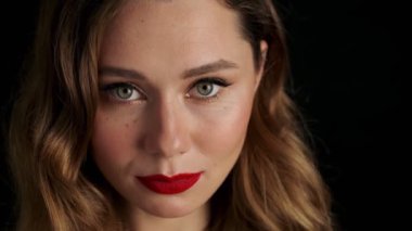 Siyah arka planda kırmızı rujlu, neşeli, genç bir kadın.