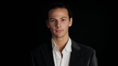 Siyah arka planda, takım elbiseli, şok olmuş genç bir adam.