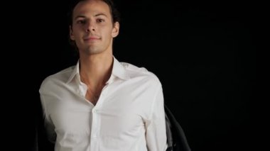 Siyah arka planda yalnız poz veren takım elbiseli yakışıklı bir genç.