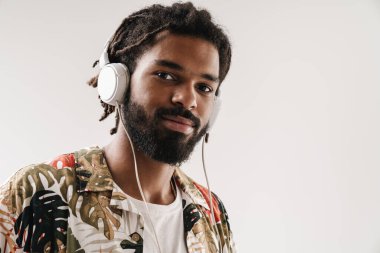 Kulaklıkla müzik dinleyen gülümseyen genç bir zencinin portresini yakından çek.