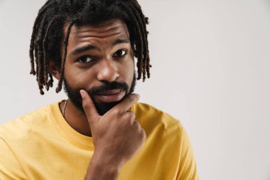 Gri duvar arkasında izole edilmiş ciddi düşünceli bir Afrikalı adamın görüntüsü.