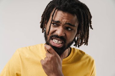 Kafası karışmış bir Afrikalı adamın, gri duvar arkasında izole edilmiş poz vermesi.