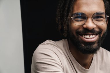 Gözlüklü, siyah beyaz duvar arkasında izole edilmiş, Afrikalı mutlu adam görüntüsü