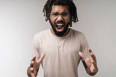 Gözlüklü, gri duvar arkaplanından izole edilmiş bağıran Afrikalı adamın görüntüsü.