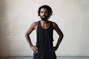 Kapalı alanda çalışırken poz veren yakışıklı Afro-Amerikan sporcunun resmi