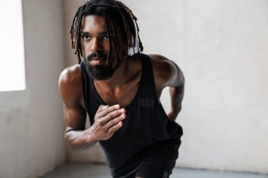 Atletik Afro-Amerikan kulaklıklı sporcunun içeride egzersiz yaparken görüntüsü