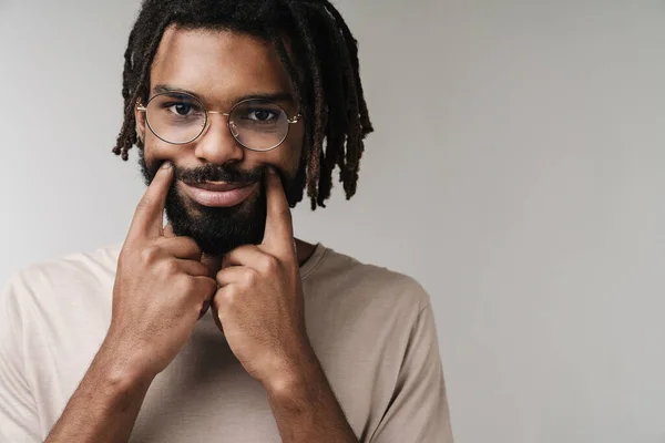 偽の笑顔を示す眼鏡で灰色の壁の背景に隔離されたアフリカ人の男の画像 — ストック写真