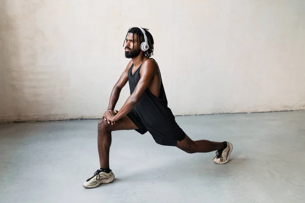 屋内で運動をしながらヘッドフォンで運動するアフリカ系アメリカ人スポーツマンのイメージ — ストック写真