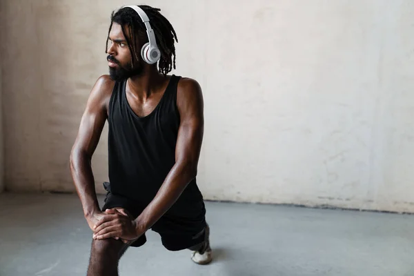 屋内で運動をしながらヘッドフォンで運動するアフリカ系アメリカ人スポーツマンのイメージ — ストック写真