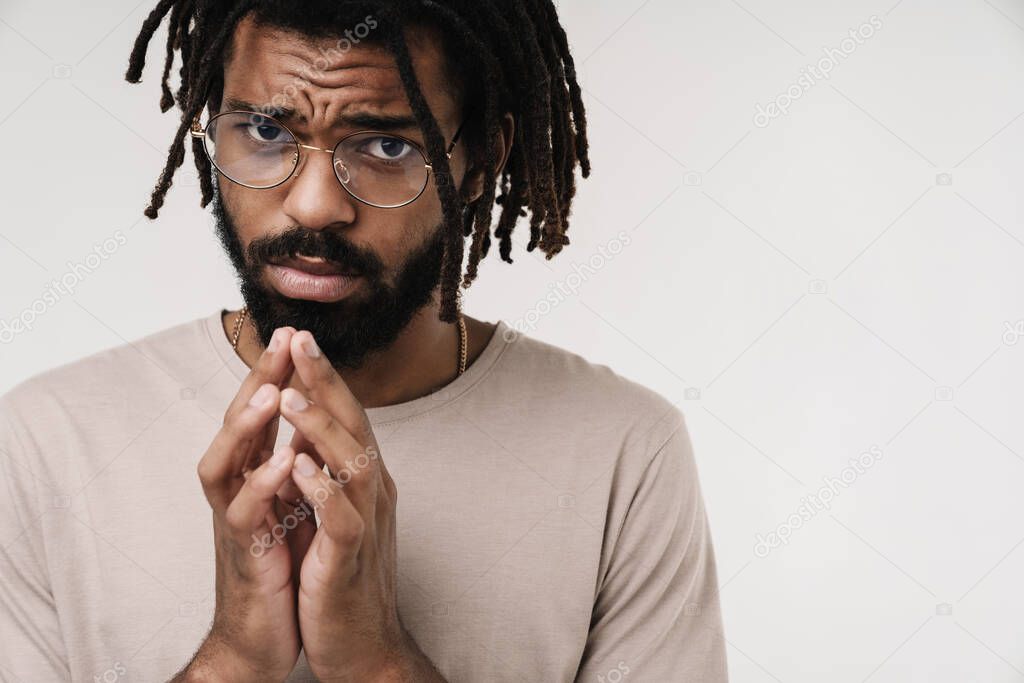 Image of guilty hopeful african guy isolated over grey wall background in eyeglasses