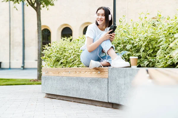 Bild Positiv Ung Asiatisk Kvinna Som Sitter Utomhus Medan Hon — Stockfoto