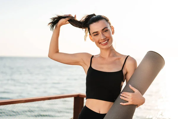 Imagen Alegre Hermosa Mujer Fitness Aire Libre Playa Sosteniendo Alfombra —  Fotos de Stock