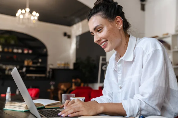 Χαμογελαστή Νεαρή Γυναίκα Που Σπουδάζει Φορητό Υπολογιστή Ενώ Κάθεται Καφετέρια — Φωτογραφία Αρχείου